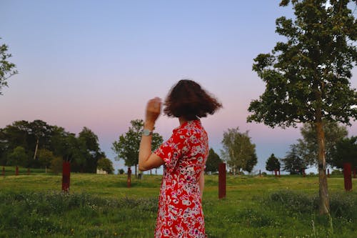 A woman in a red dress is standing in a field