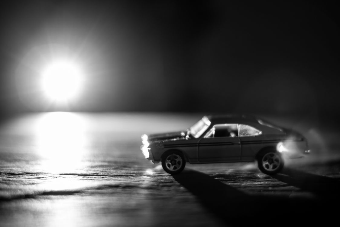 Free A dramatic black and white photo featuring a toy car with bright light creating a striking contrast. Stock Photo