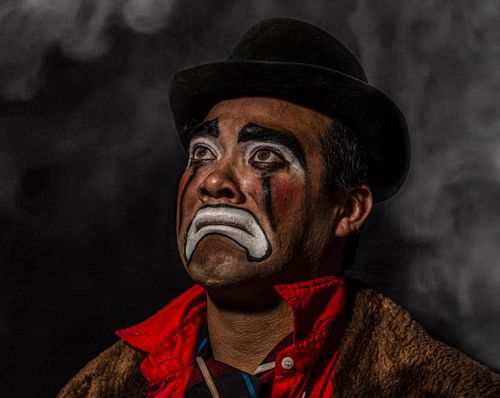 Free Close-up studio portrait of a sad clown with painted face looking upwards, capturing deep emotion. Stock Photo