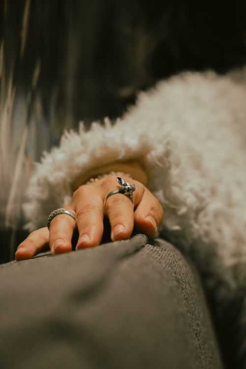 Free Warm close-up of a woman's hand with rings on fingers, emphasizing the texture of a fluffy jacket. Stock Photo