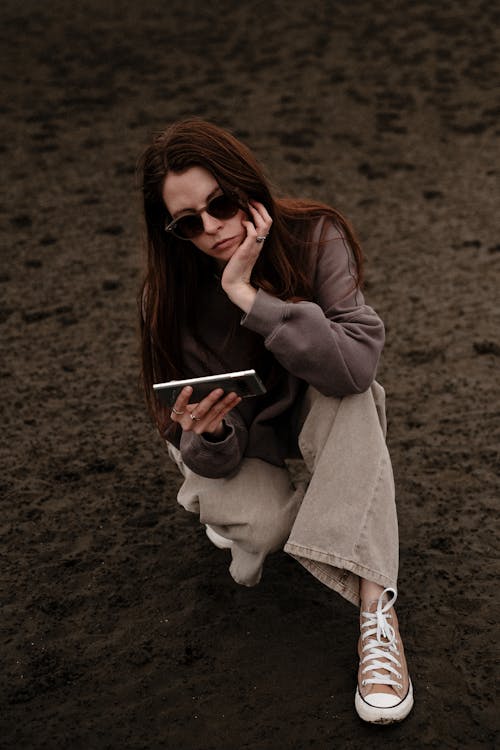 A woman sitting on the ground with her phone