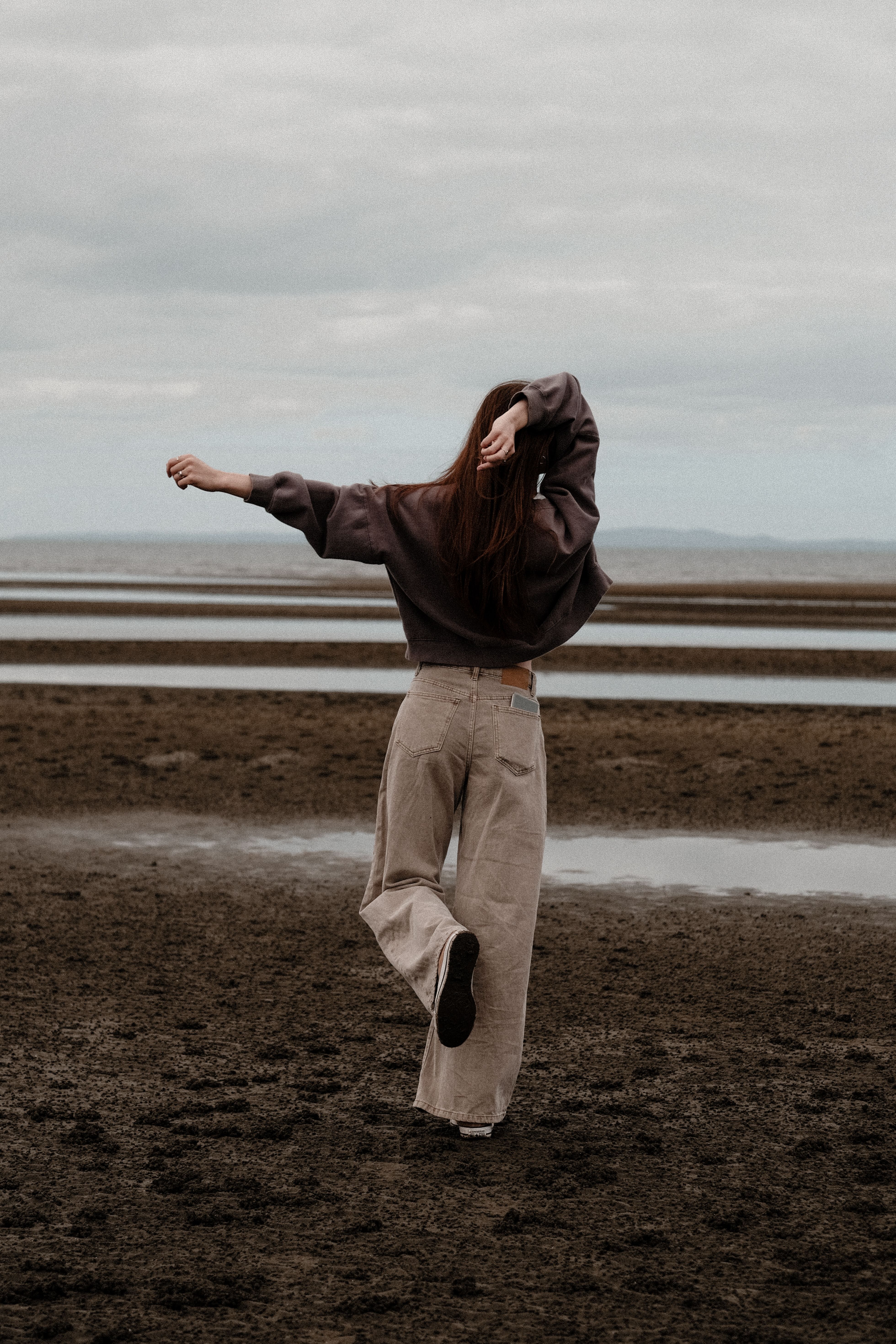 A woman standing on the beach with her arms outstretched · Free Stock Photo