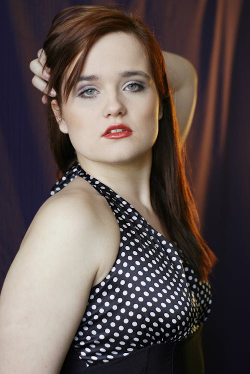 A woman with red hair and black and white polka dot dress