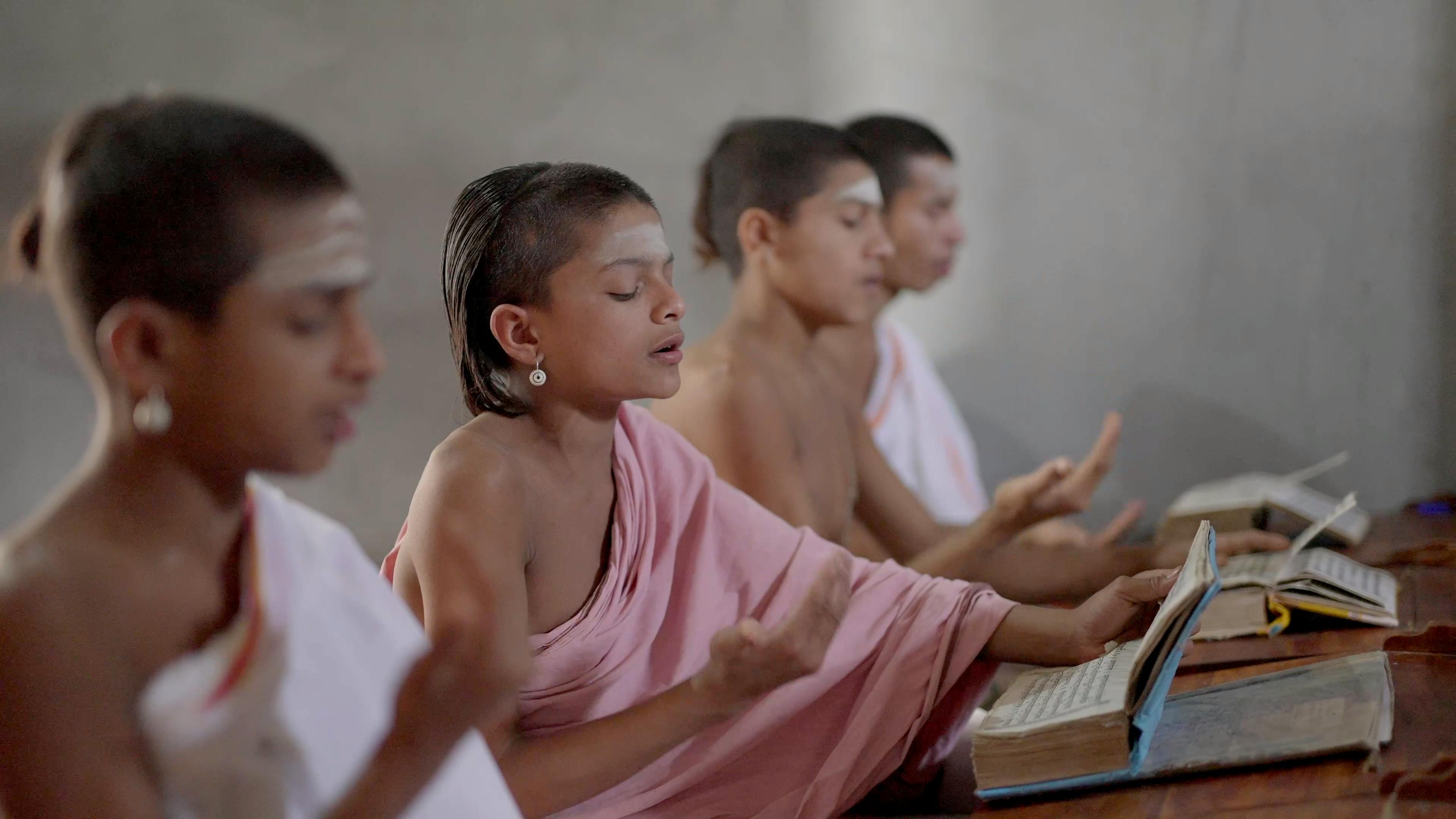 Four young monks studying religious texts with concentration in a serene setting.