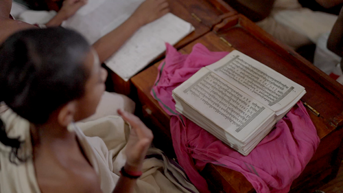 Free A young student is studying a religious text in a traditional classroom setting, focused and engaged. Stock Photo