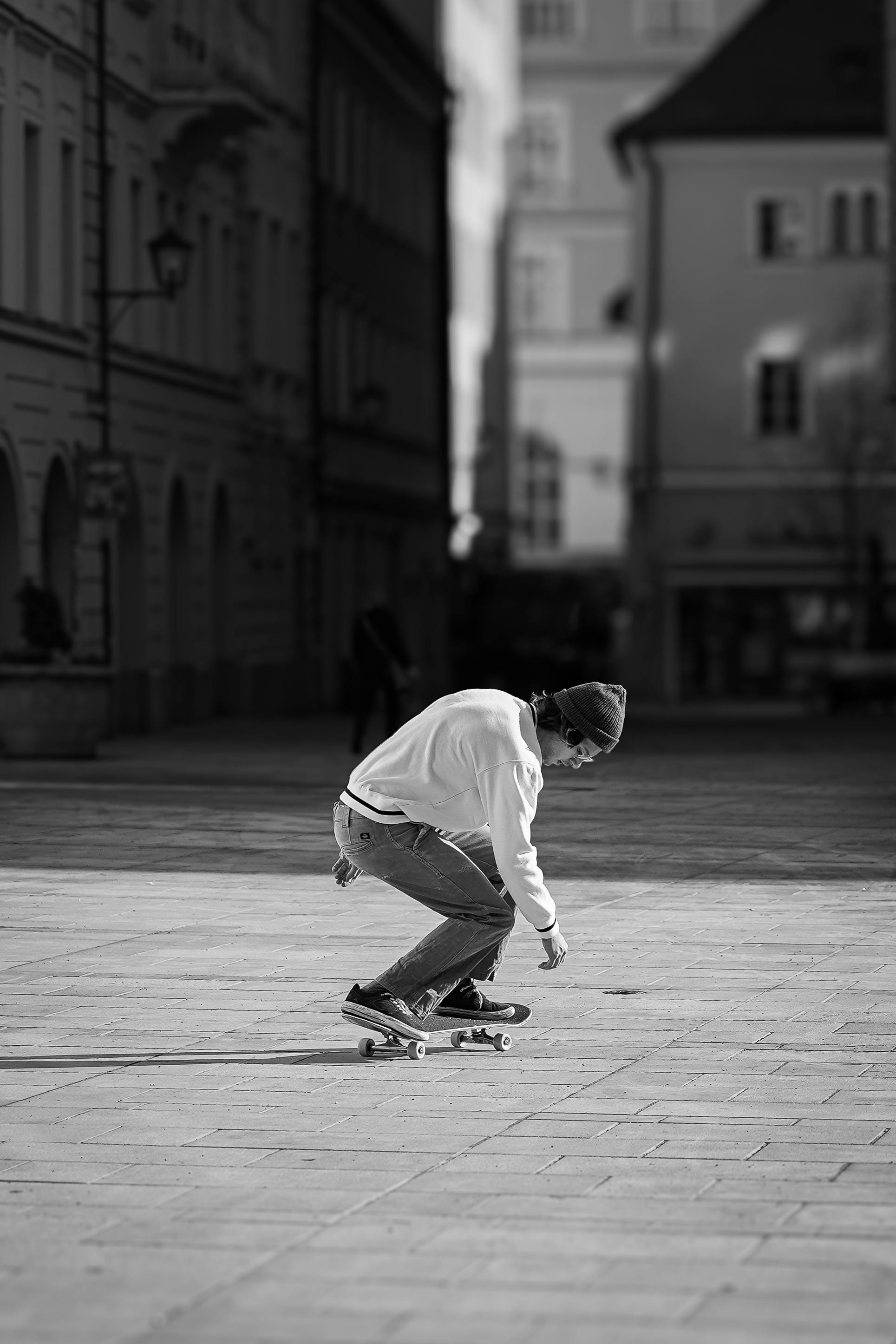 Skateboarder executing a trick in a city plaza in black and white.