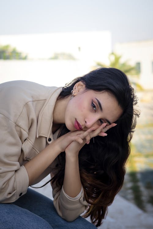 Young Brunette in a Brown Jacket Sitting Outside 