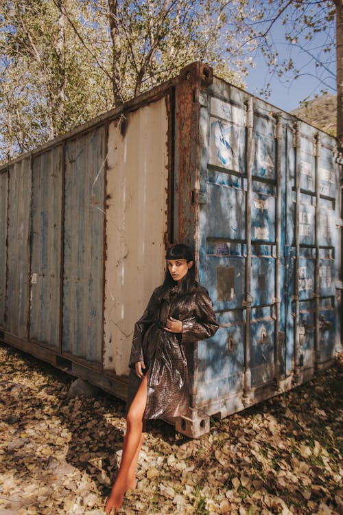 A woman in a black coat standing next to a shipping container
