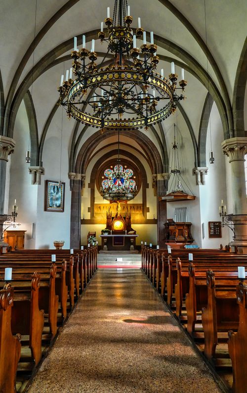 Free Beautiful interior view of a historic church in Meran, Italy with ornate chandeliers and empty benches. Stock Photo