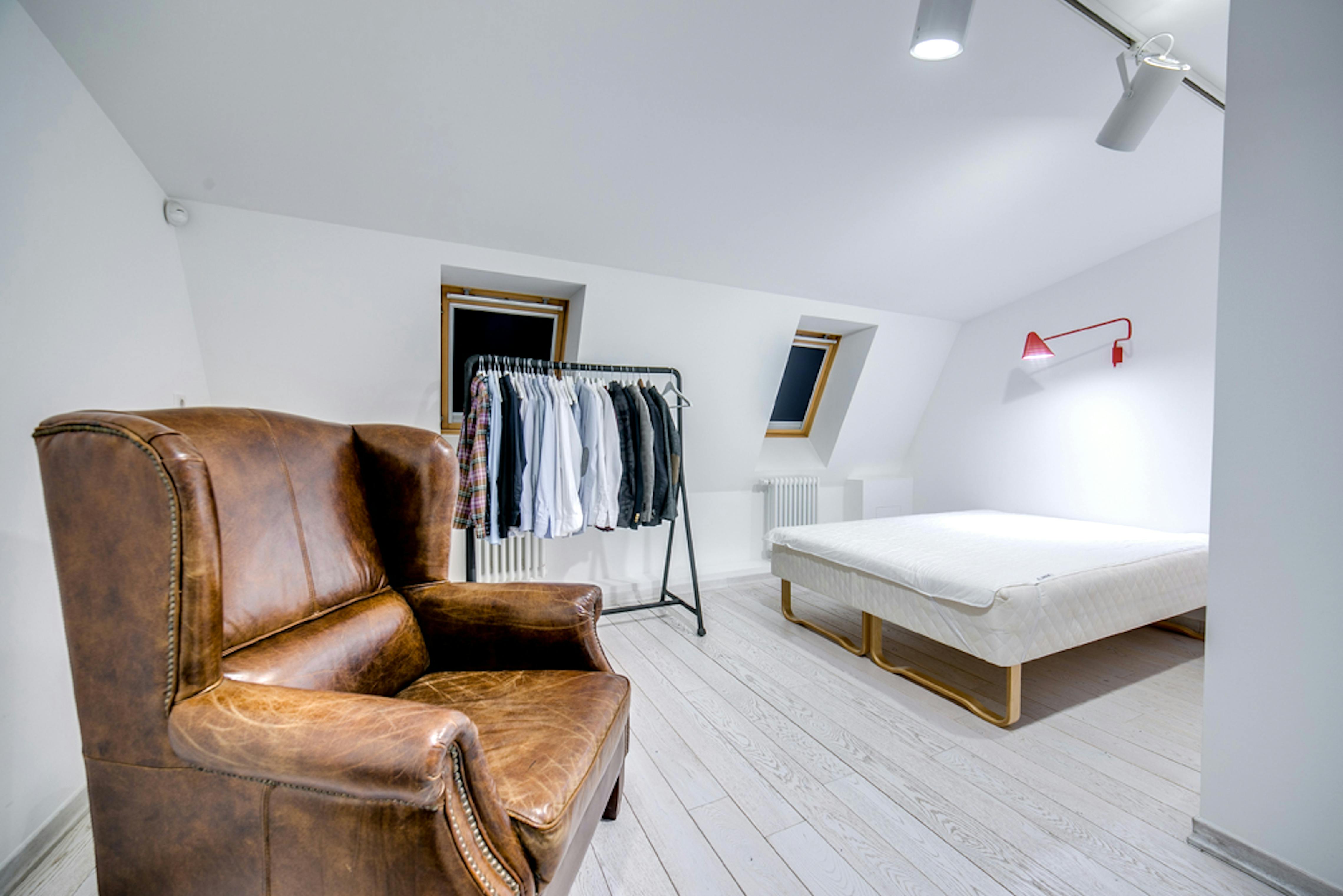 Offenes Kleidersystem an einer hohen Wand in einem schmalen Dachschrägenzimmer