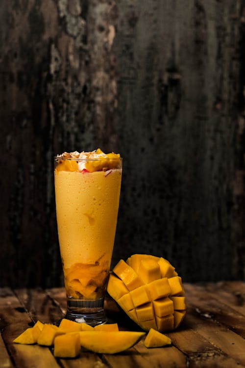 Mango smoothie with mango slices on a wooden table