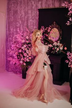 Stylish portrait of a woman in a pink tulle dress surrounded by flowers.