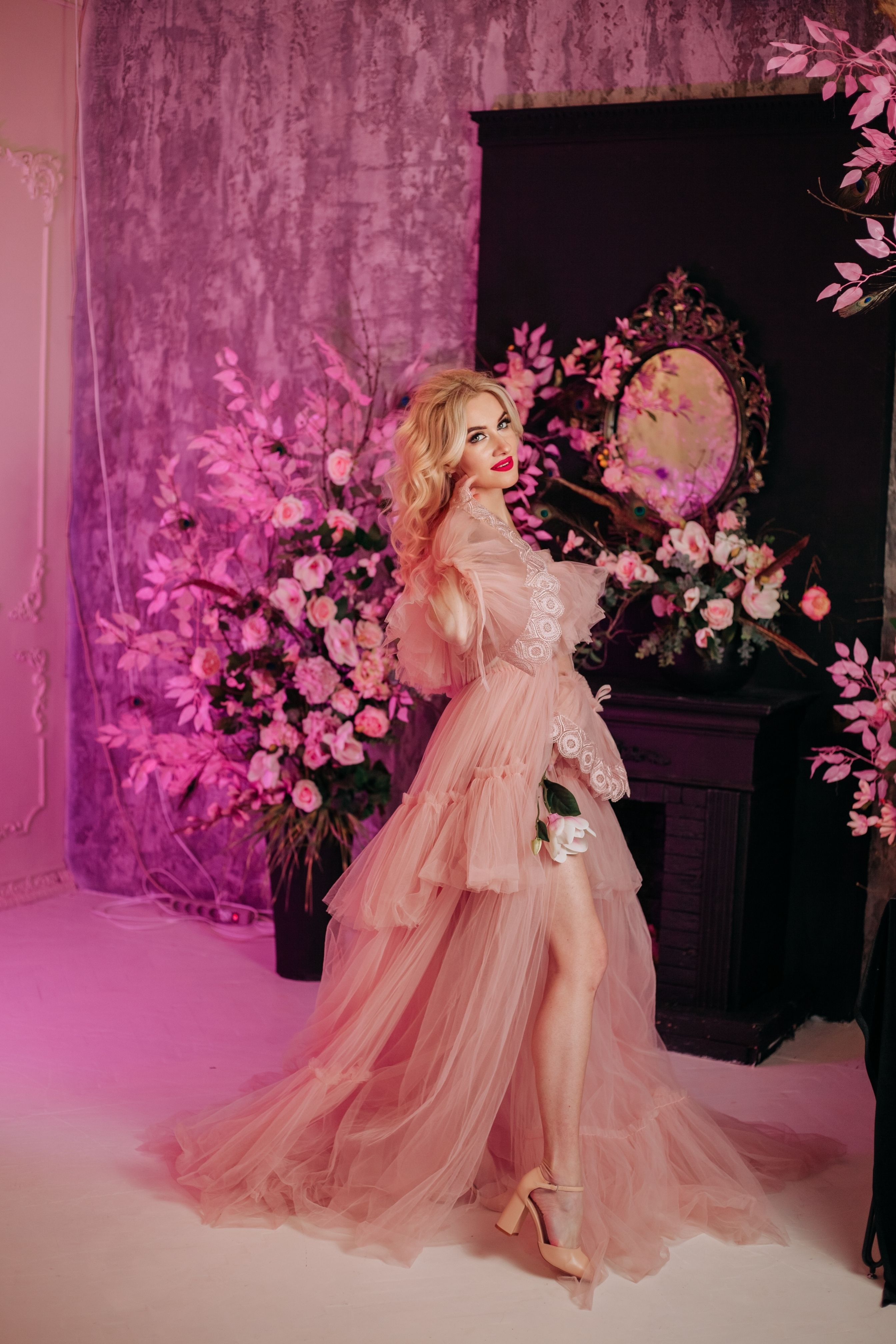 Young Woman Posing in a Pink Tulle Dress among Flower Arrangements