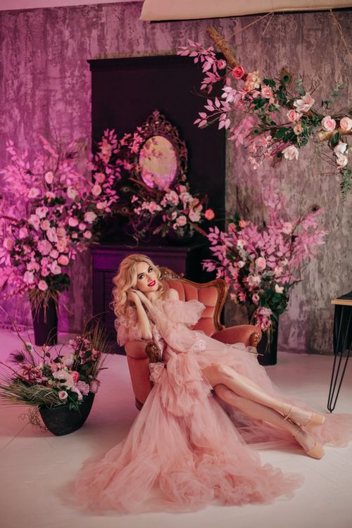 Free A stylish woman in a pink dress sitting in a beautifully decorated floral room. Stock Photo