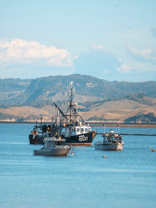 View of a Fishing Vessel and Two Smaller Boats on a Body of Water 