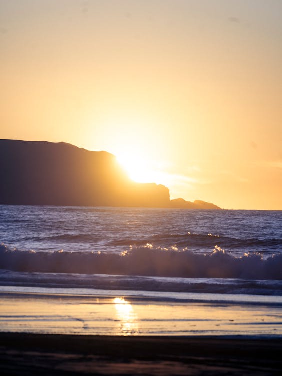 A person standing on the beach at sunset