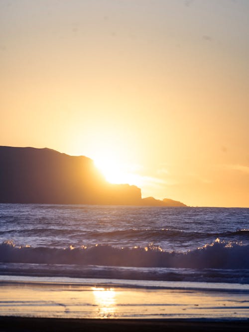 A person standing on the beach at sunset