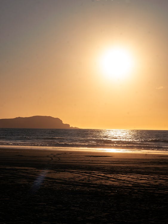 A person walking on the beach at sunset