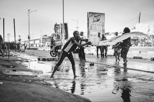 A man is walking through a puddle with a skateboard