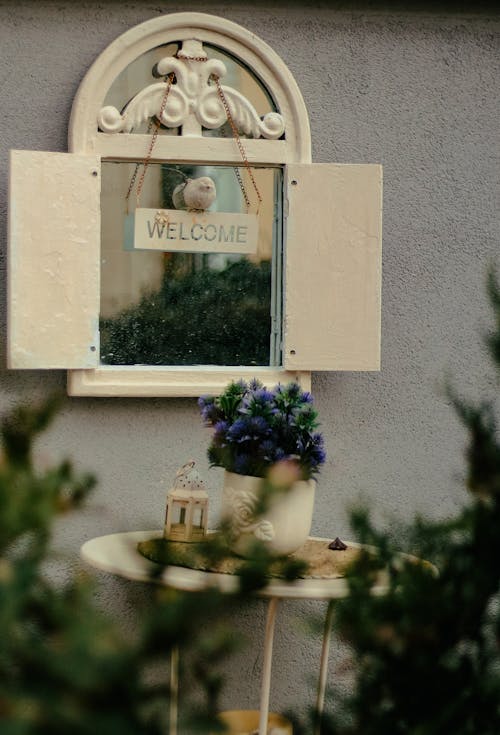 A Potted Plant Standing on a Table by the Window with a Welcome Sign 