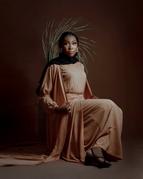 A woman in a tan dress sitting on a chair