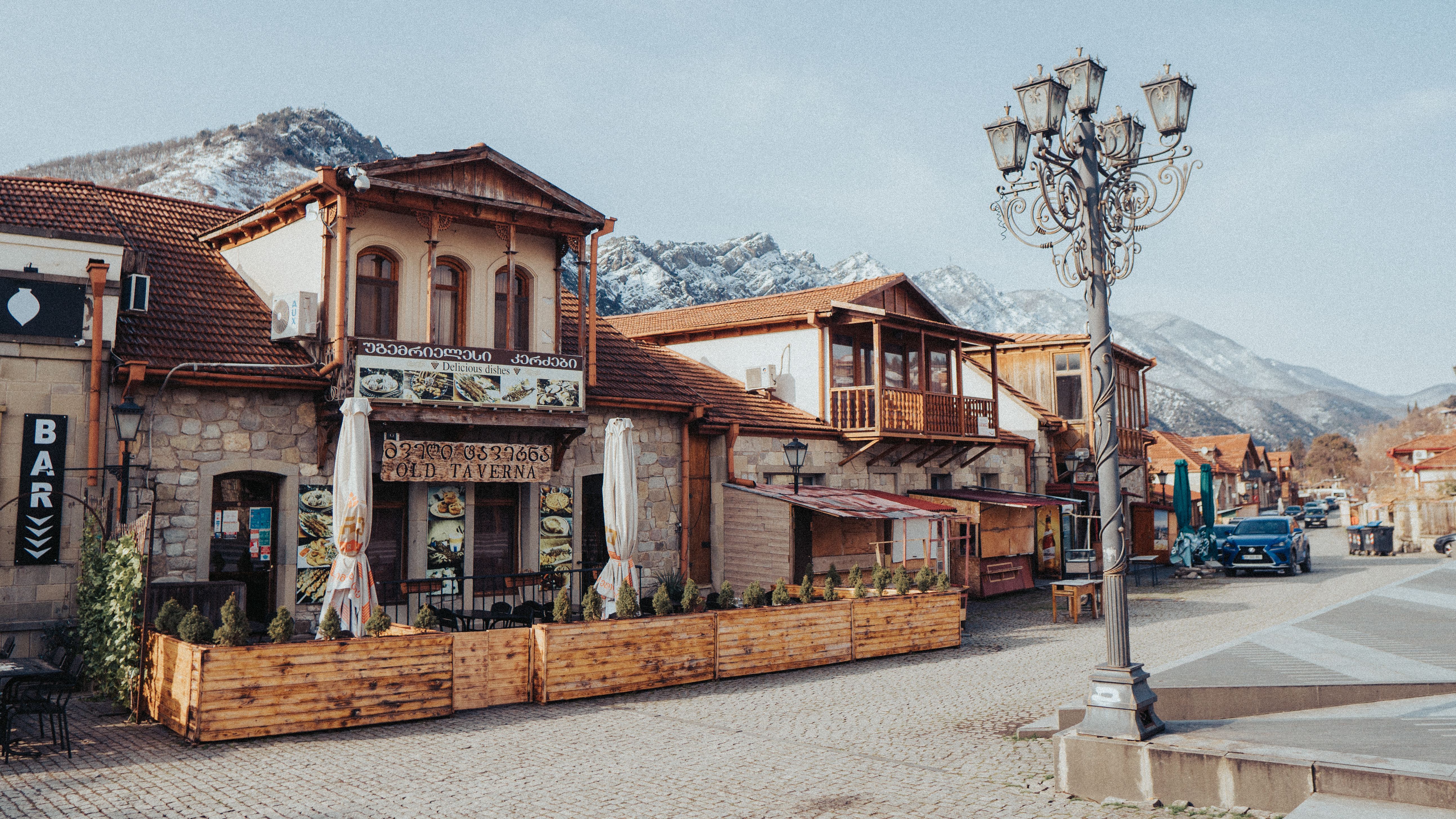 digital nomad working from a rustic cafe in Tbilisi with traditional Georgian architecture and cobblestone streets