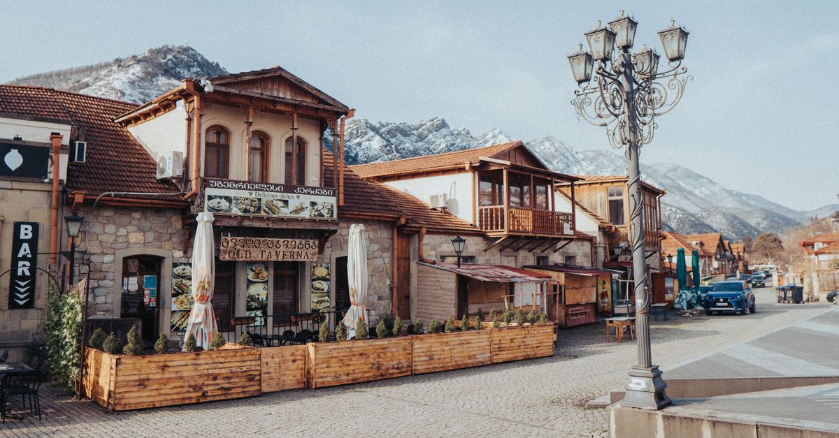 digital nomad working from a rustic cafe in Tbilisi with traditional Georgian architecture and cobblestone streets
