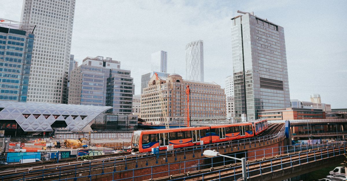 A vibrant view of London's Canary Wharf with modern skyscrapers and a passing train.