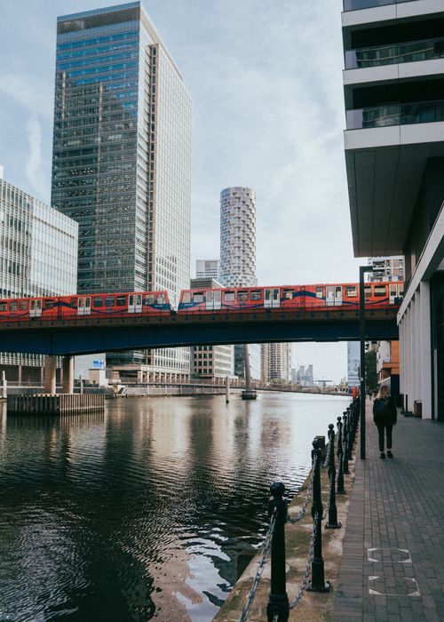 Free View of towering skyscrapers and a red train crossing a bridge over a river in London. Stock Photo