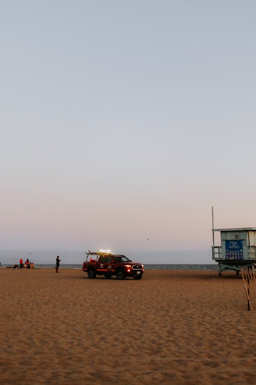 A red truck is parked on the beach