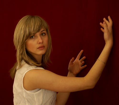 A woman reaching out to touch a red wall