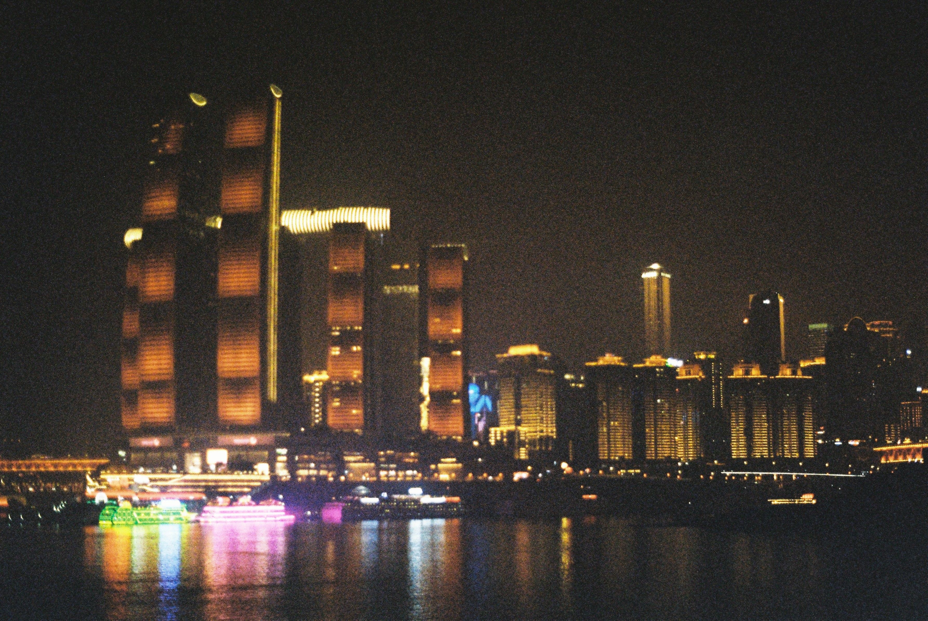 A city skyline lit up at night with boats in the water · Free Stock Photo