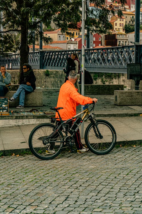 A man in an orange jacket riding a bike