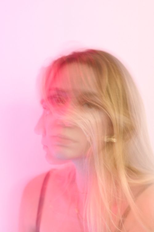 Free Artistic blurred portrait of a woman with pink hues creating a dreamy effect. Stock Photo