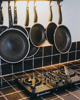 A unique kitchen scene featuring hanging pans and a DJ mixer on a tiled countertop.