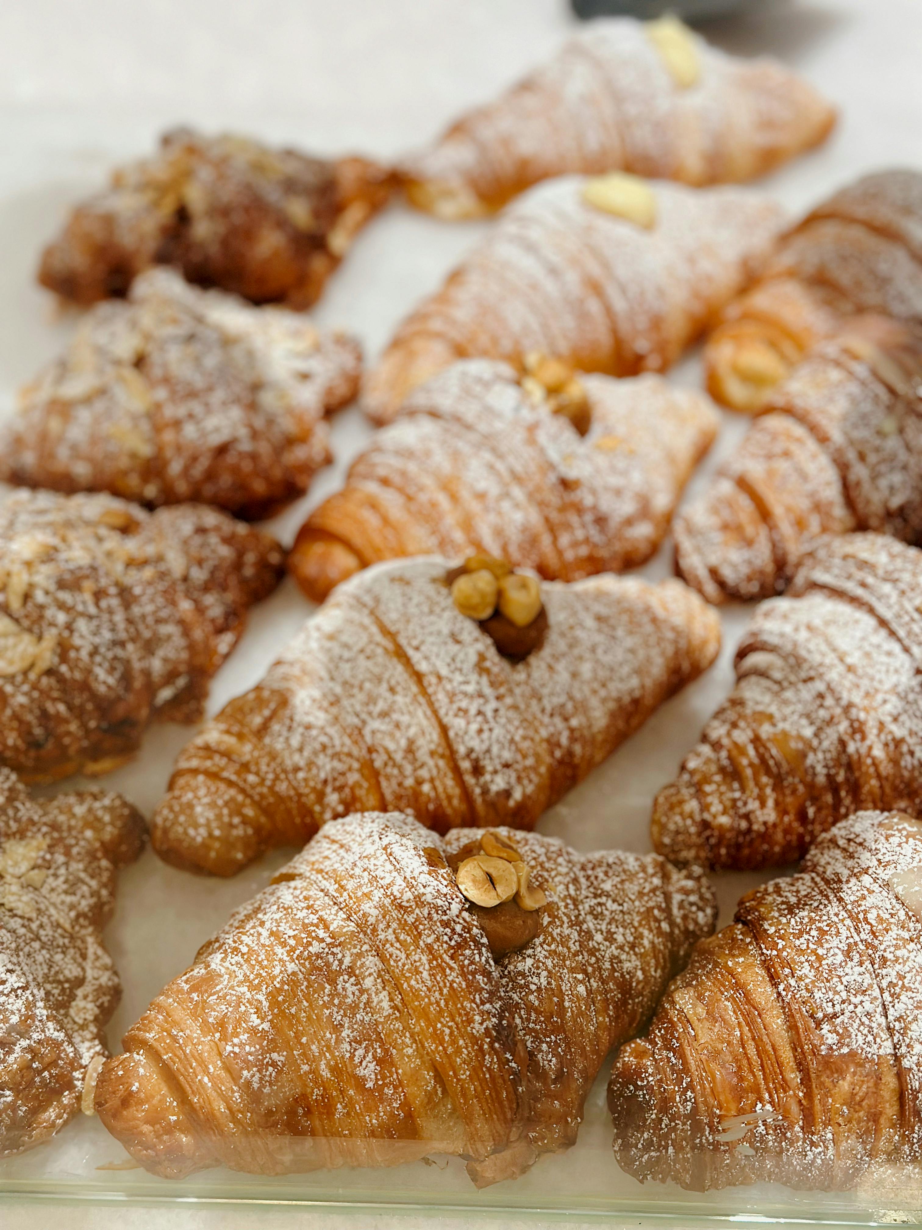 Freshly baked croissants topped with powdered sugar and peanuts, perfect for a delightful snack.