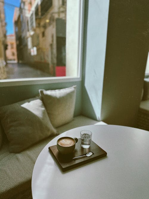 A coffee cup sitting on a table in front of a window