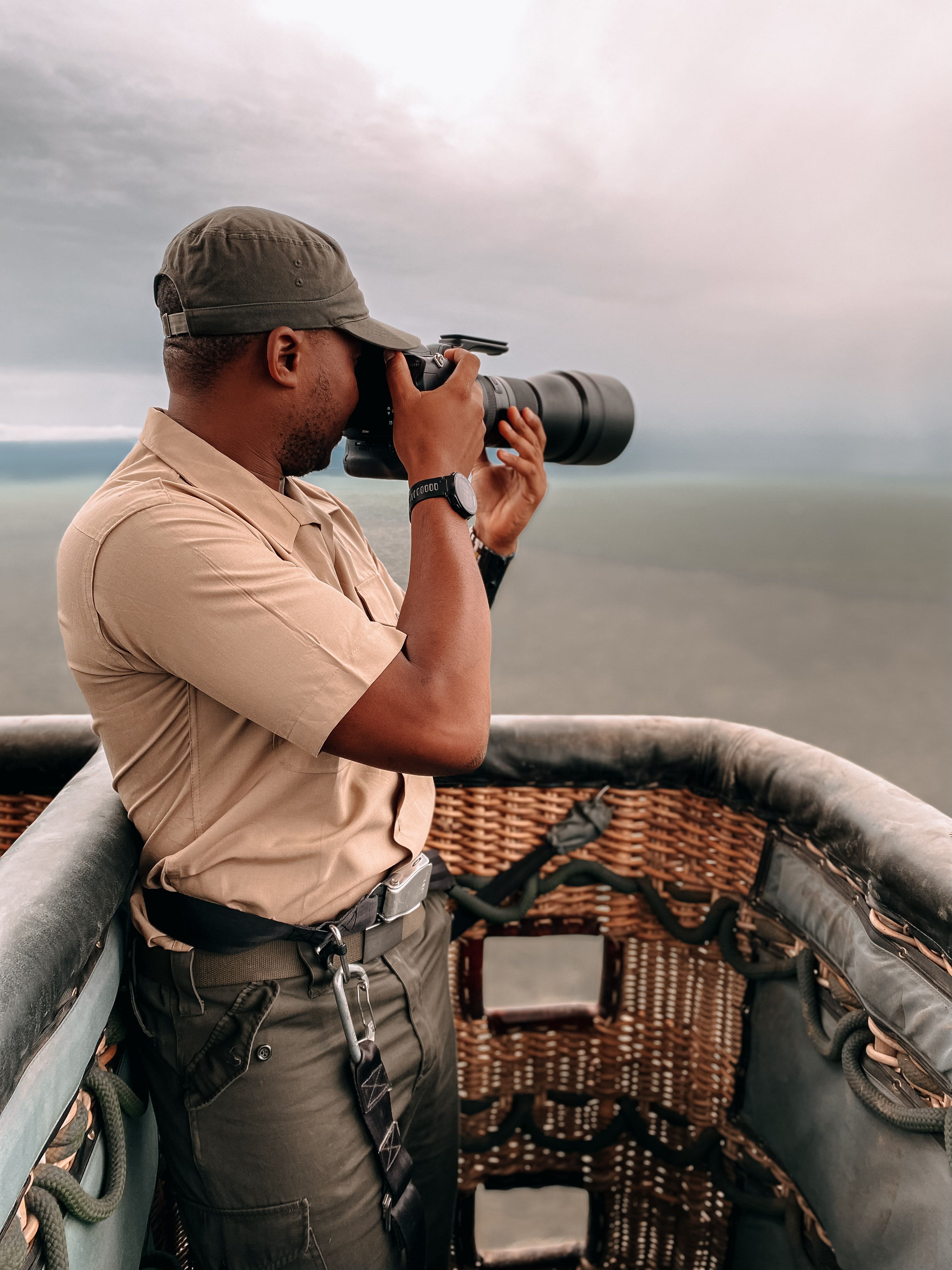 Man photographing landscape from a hot air balloon during a safari adventure.