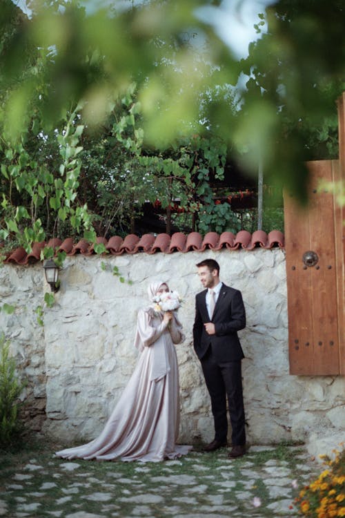 A bride and groom standing in front of a stone wall