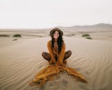一位时尚女士坐在迪拜的广阔沙漠中微笑