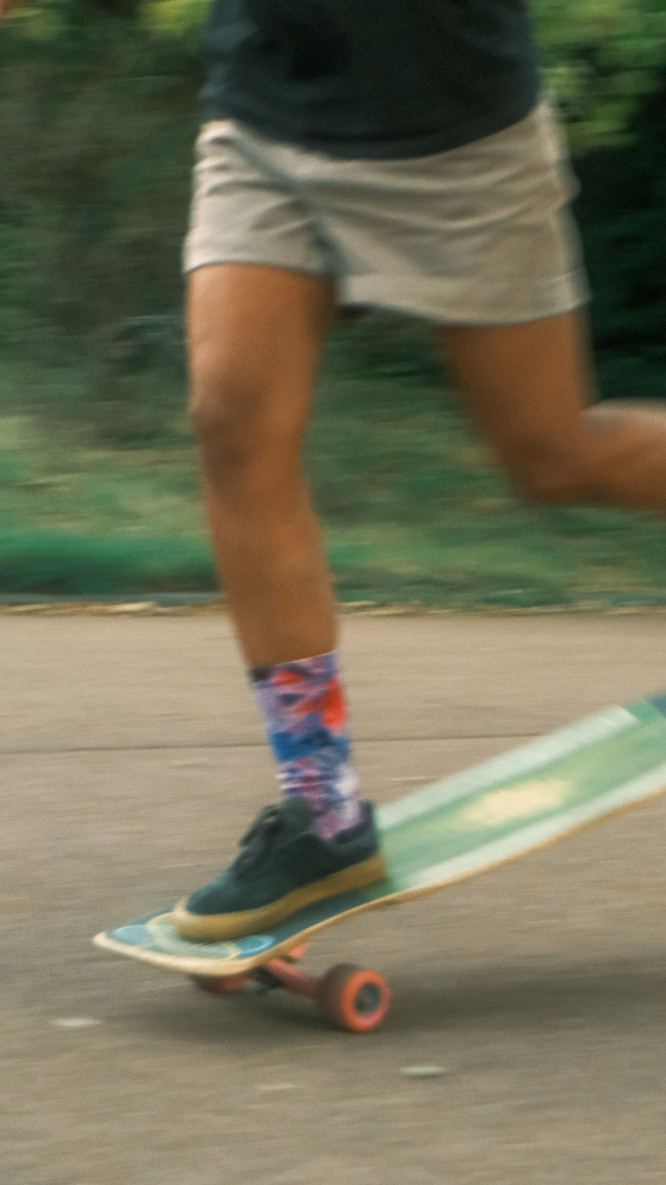Close-up of a skateboarder in motion showcasing colorful socks and skateboard on a city street.