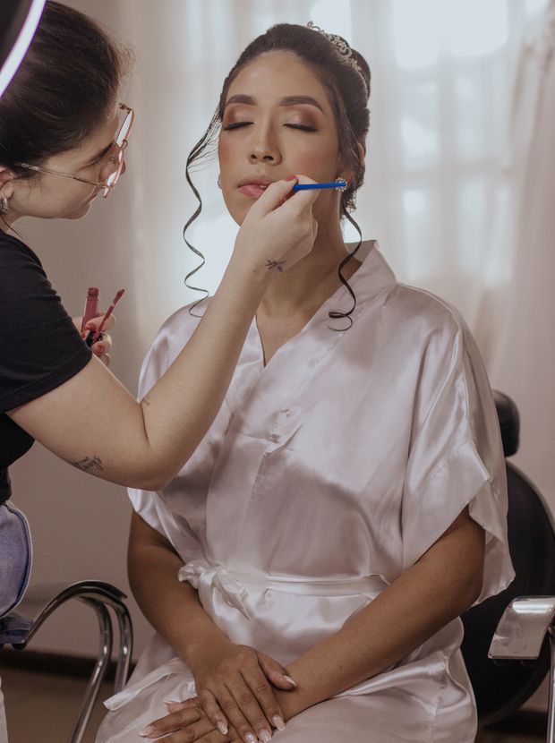 Bride having her makeup done by a beautician before her wedding