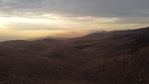 A view of the desert at sunset with mountains in the background