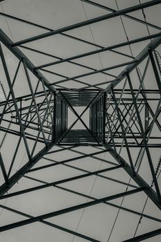 Dramatic underside view of a steel transmission tower showcasing geometric patterns and industrial design.
