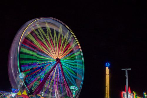 Free A vibrant Ferris wheel spinning at night, illuminating the urban skyline with colorful lights. Stock Photo