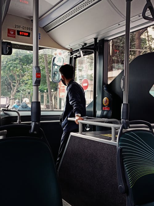 A man is standing on the bus looking out the window