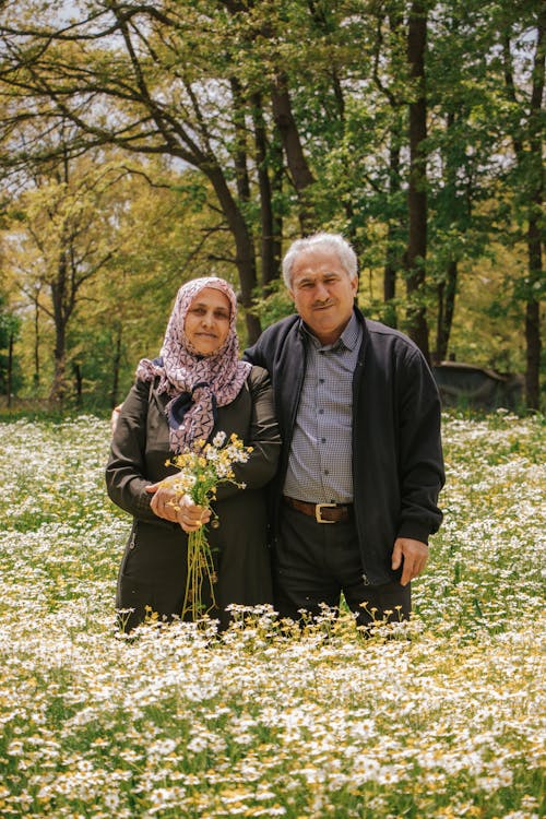 An older couple standing in a field of flowers