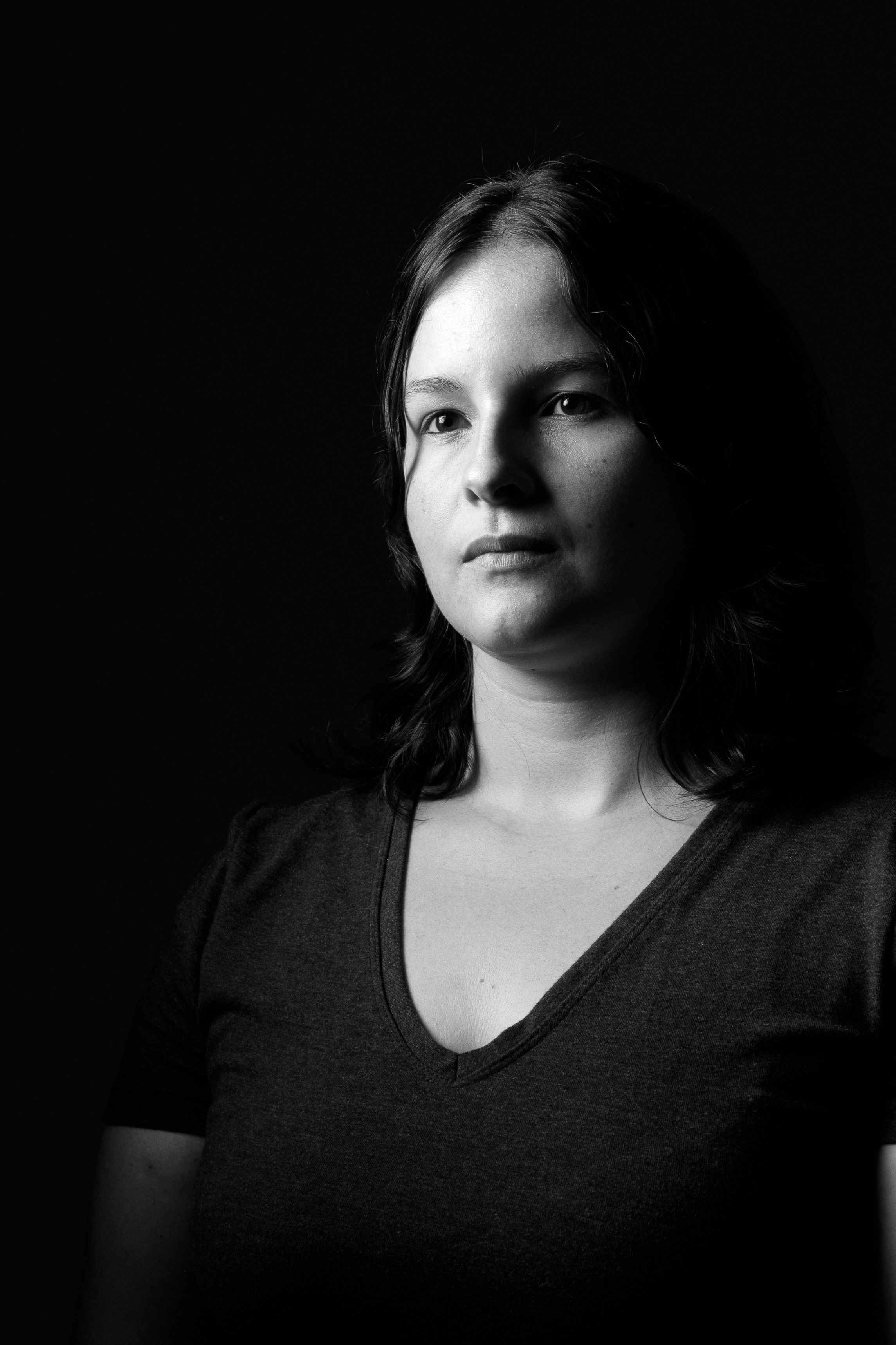 Moody black and white portrait of a teenager with long hair in a studio setting.