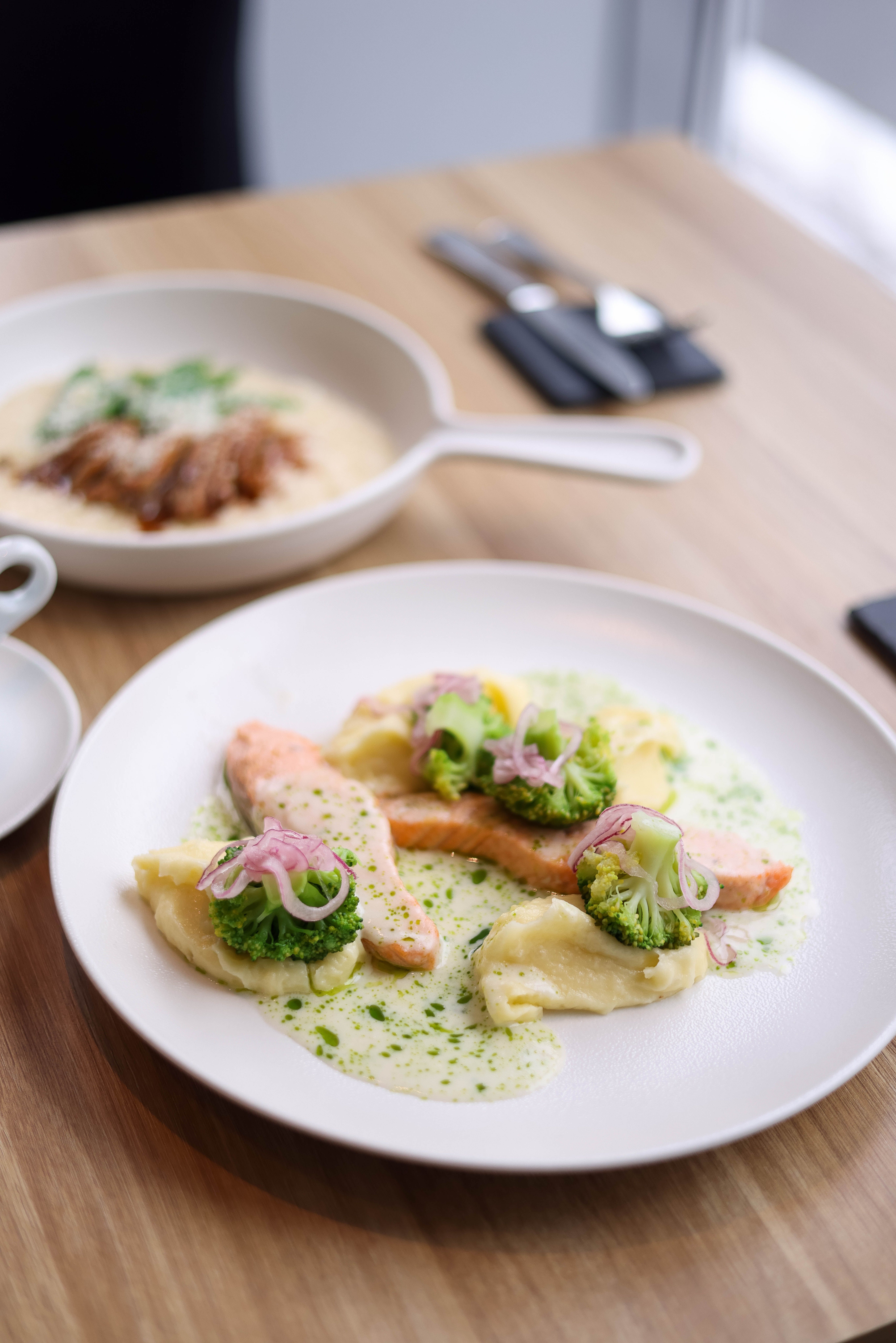 Appetizing gourmet salmon dish with vegetables in a creamy sauce on a wooden table.