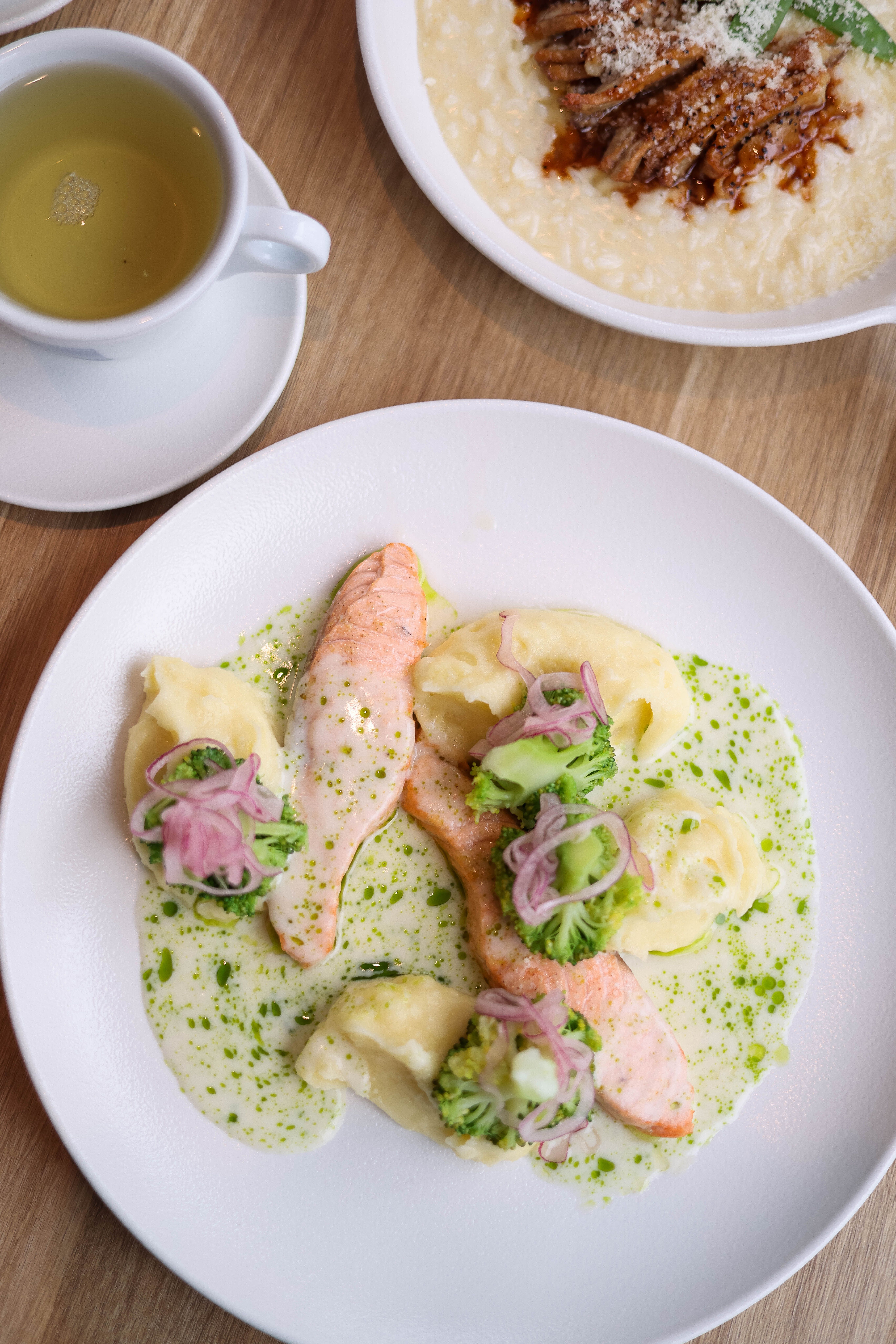 A delicious plate of salmon with vegetables, garnished in sauce, served with tea.